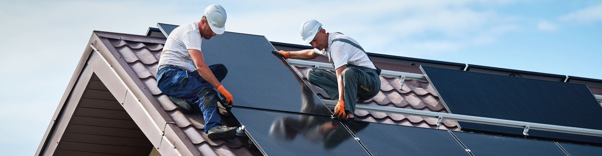 Deux installateurs qui posent des panneaux solaires sur le toît d'une maison arrêté S21